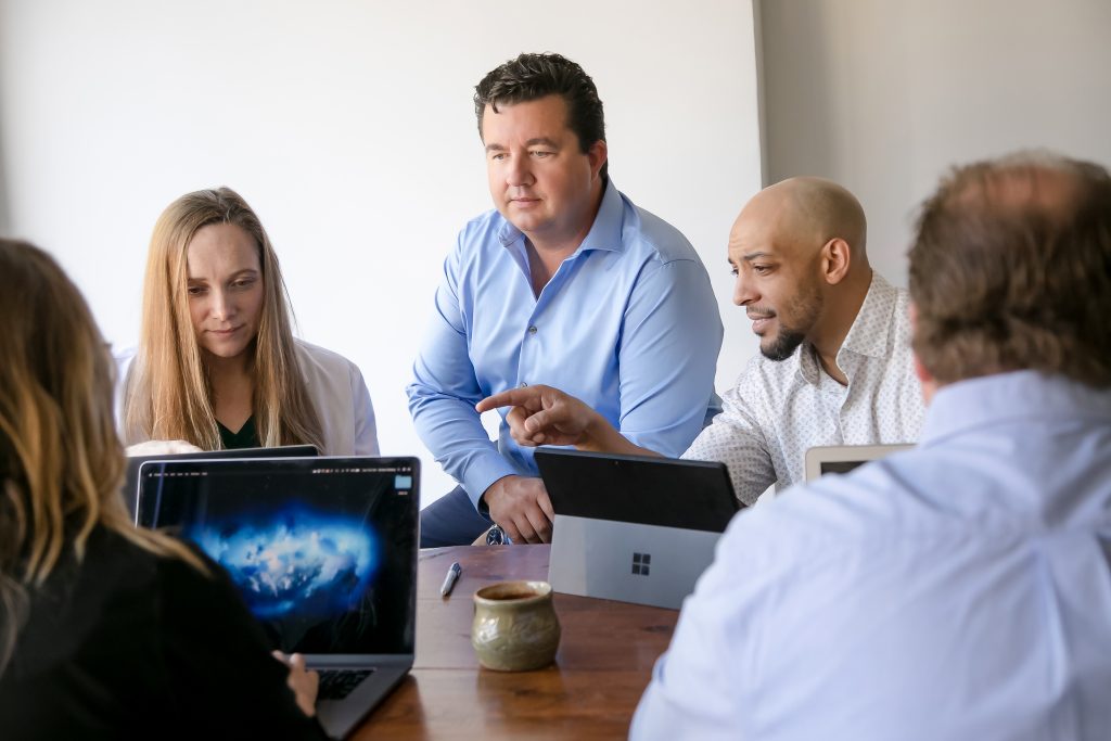 A man overseeing a team of people working on their computers at a desk